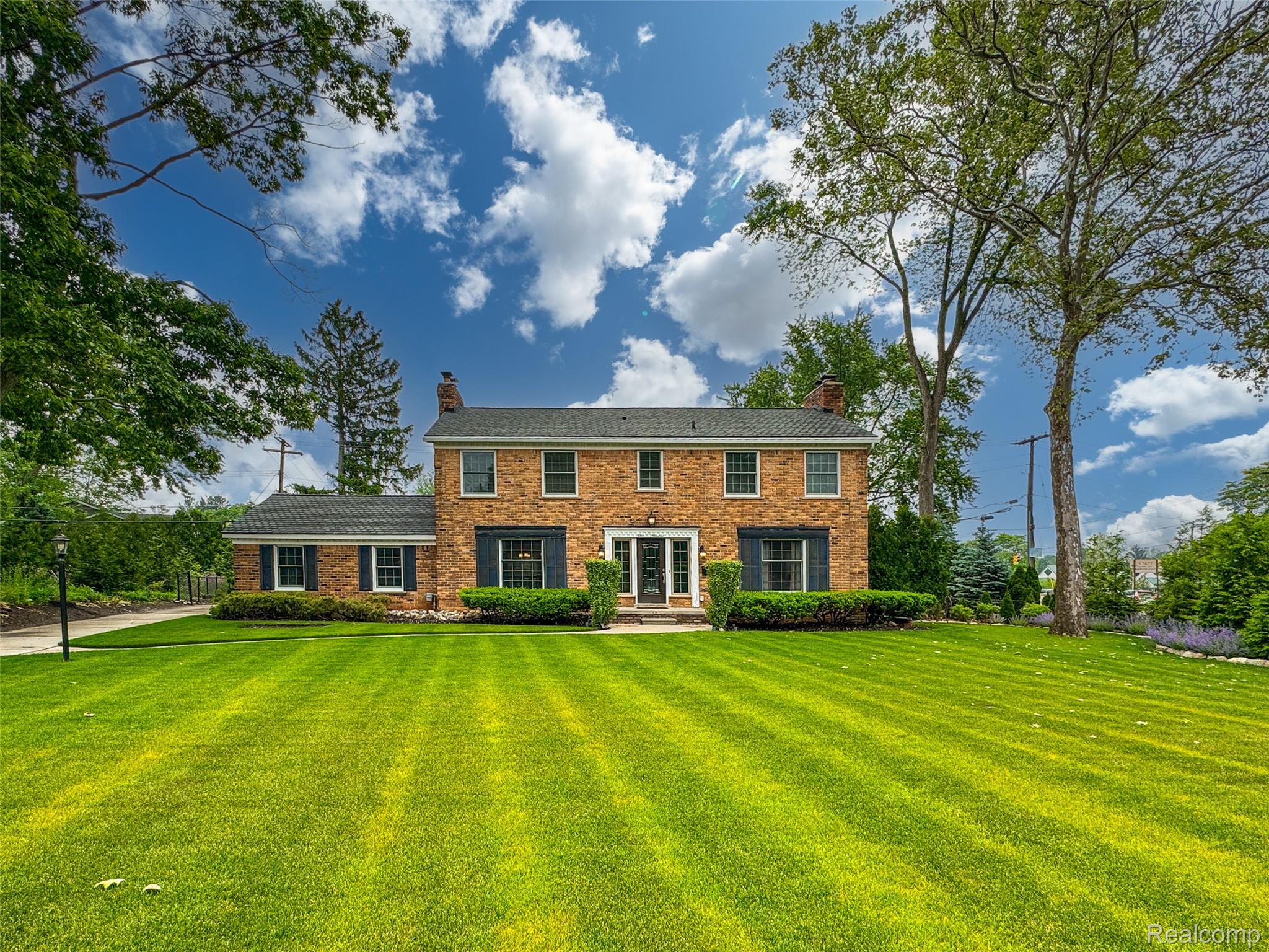 View of front of house with a chimney, a front yard, and brick siding