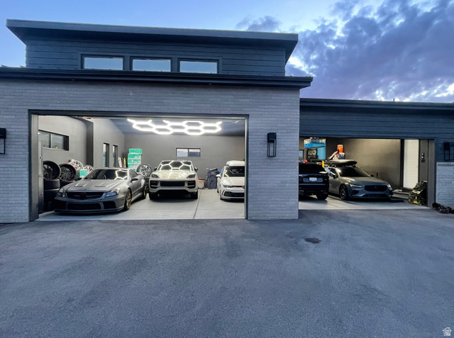3667 Little Cottonwood Road, Unit 1 Sandy, UT 84092 - Photo 48 of 49 Multi-bay garage featuring modern hexagonal ceiling lighting, dark brick exterior accents, and an asphalt driveway