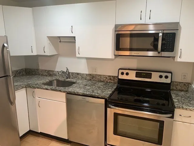 a kitchen with stainless steel appliances granite countertop a stove microwave and sink