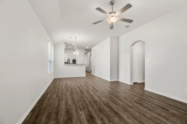 an empty room with wooden floor and a ceiling fan