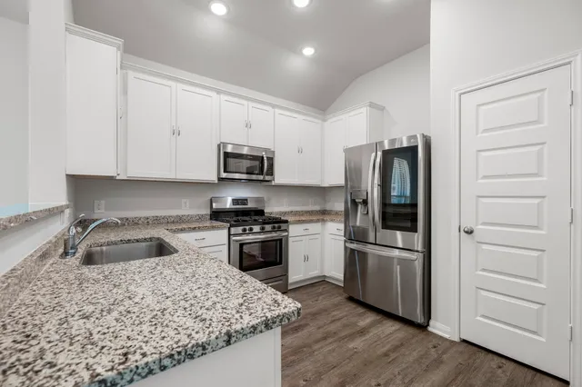 a kitchen with granite countertop a refrigerator stove and sink
