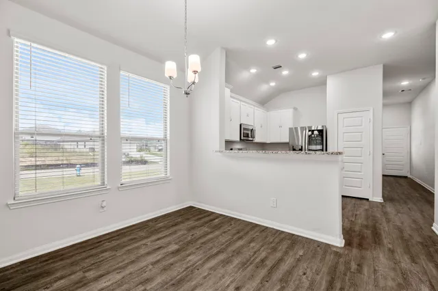 a view of a kitchen and an empty room with wooden floor