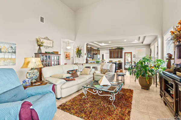 a living room with furniture potted plant and kitchen view