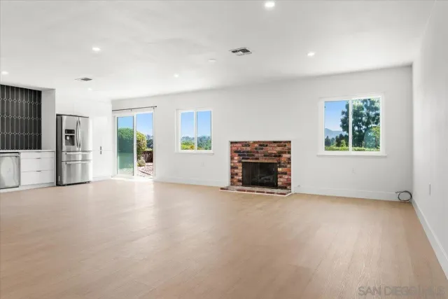 an empty room with windows and fireplace