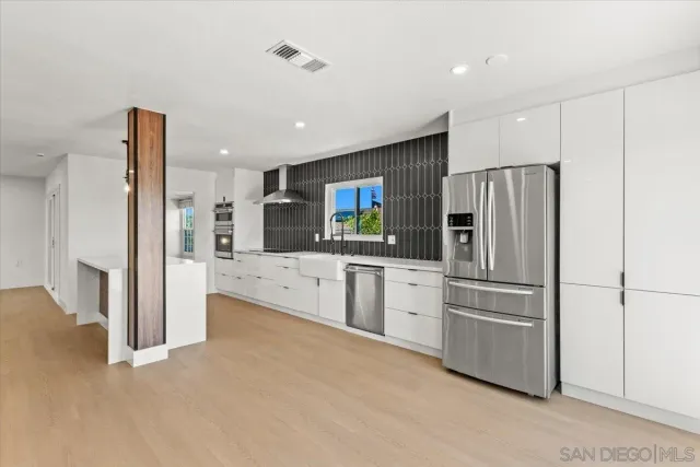 a large kitchen with kitchen island a sink stainless steel appliances and a chandelier