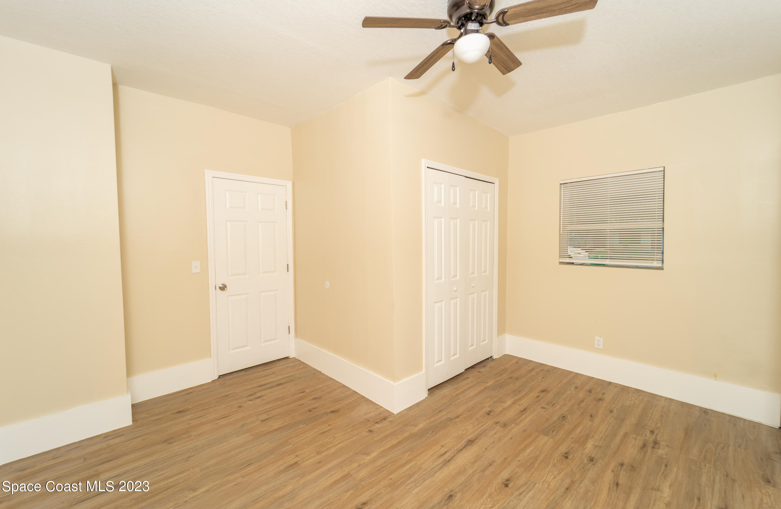 254 Lime Street Cocoa, FL 32926 - Photo 12 of 16 a view of an empty room with wooden floor and a ceiling fan