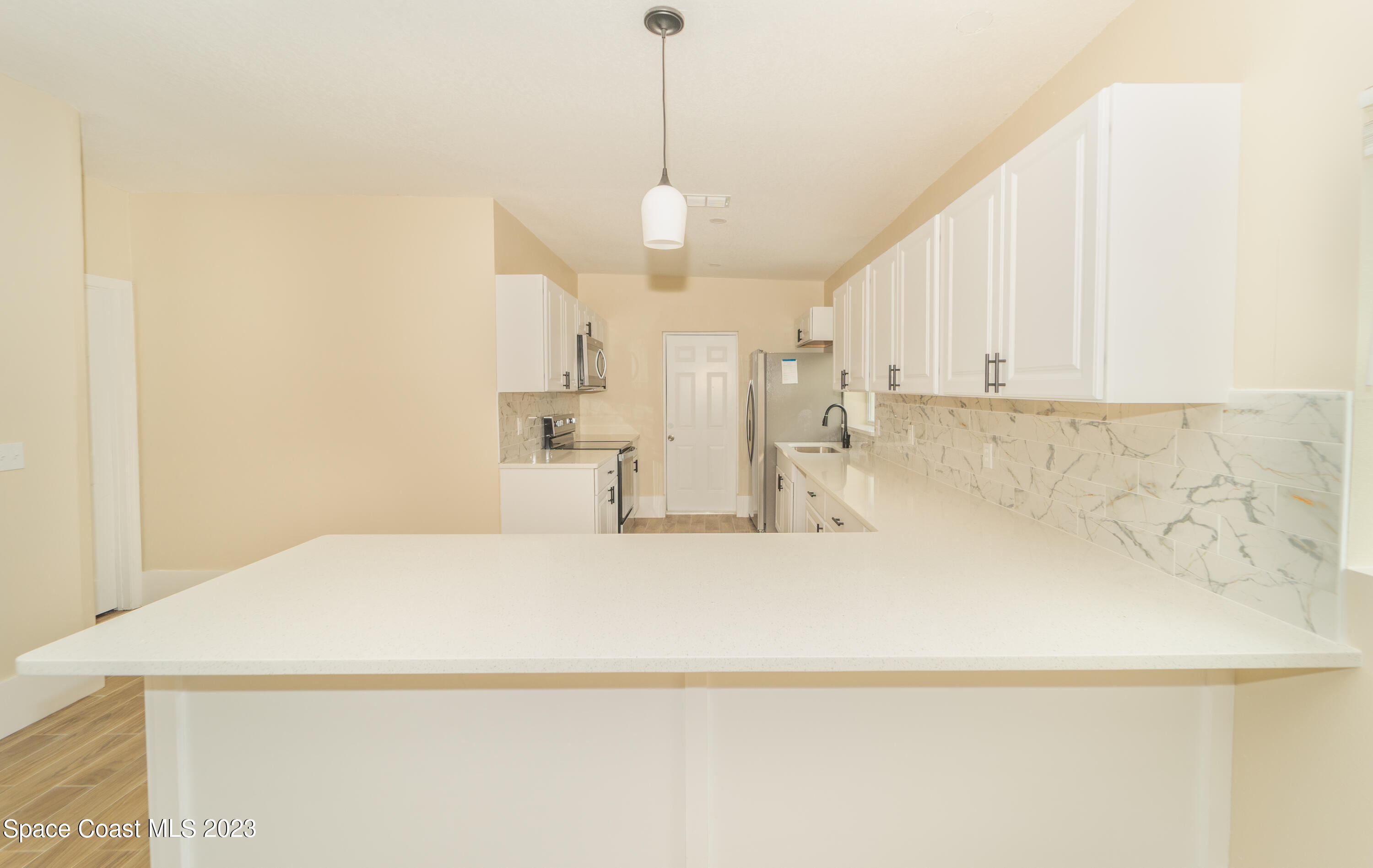 254 Lime Street Cocoa, FL 32926 - Photo 2 of 16 a large white kitchen with white cabinets and a chandelier