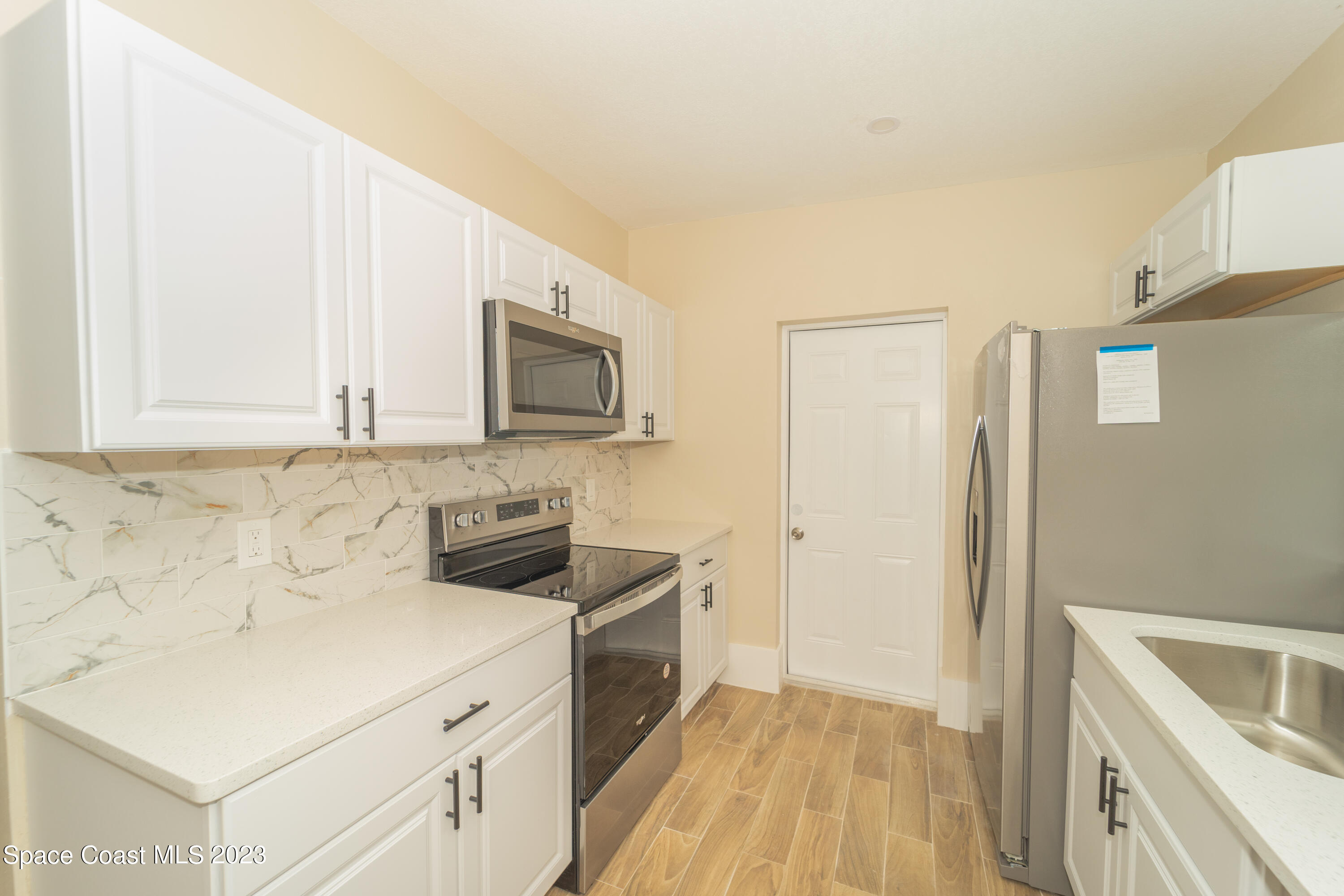 254 Lime Street Cocoa, FL 32926 - Photo 4 of 16 a kitchen with a sink a microwave a refrigerator and cabinets