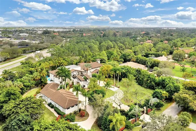 an aerial view of residential houses with outdoor space and trees