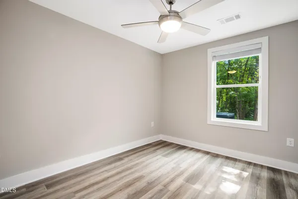 an empty room with a window and ceiling fan