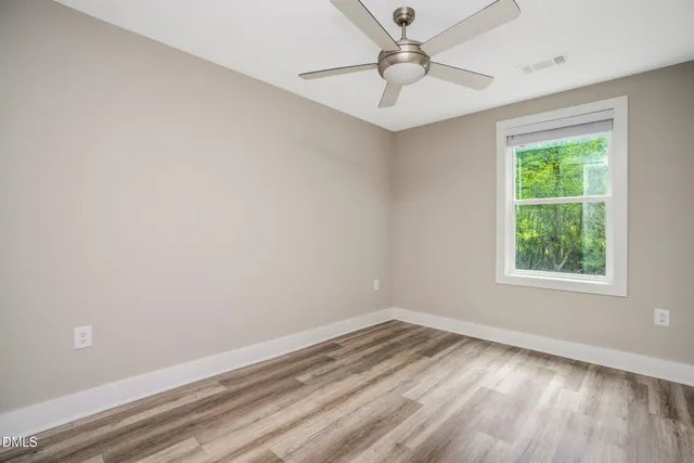 an empty room with a window and a fan