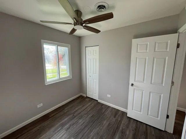 an empty room with wooden floor fan and windows