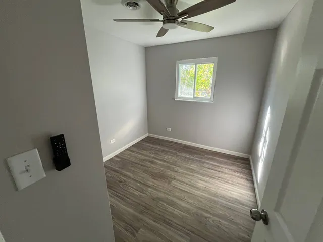 a view of empty room with wooden floor and fan