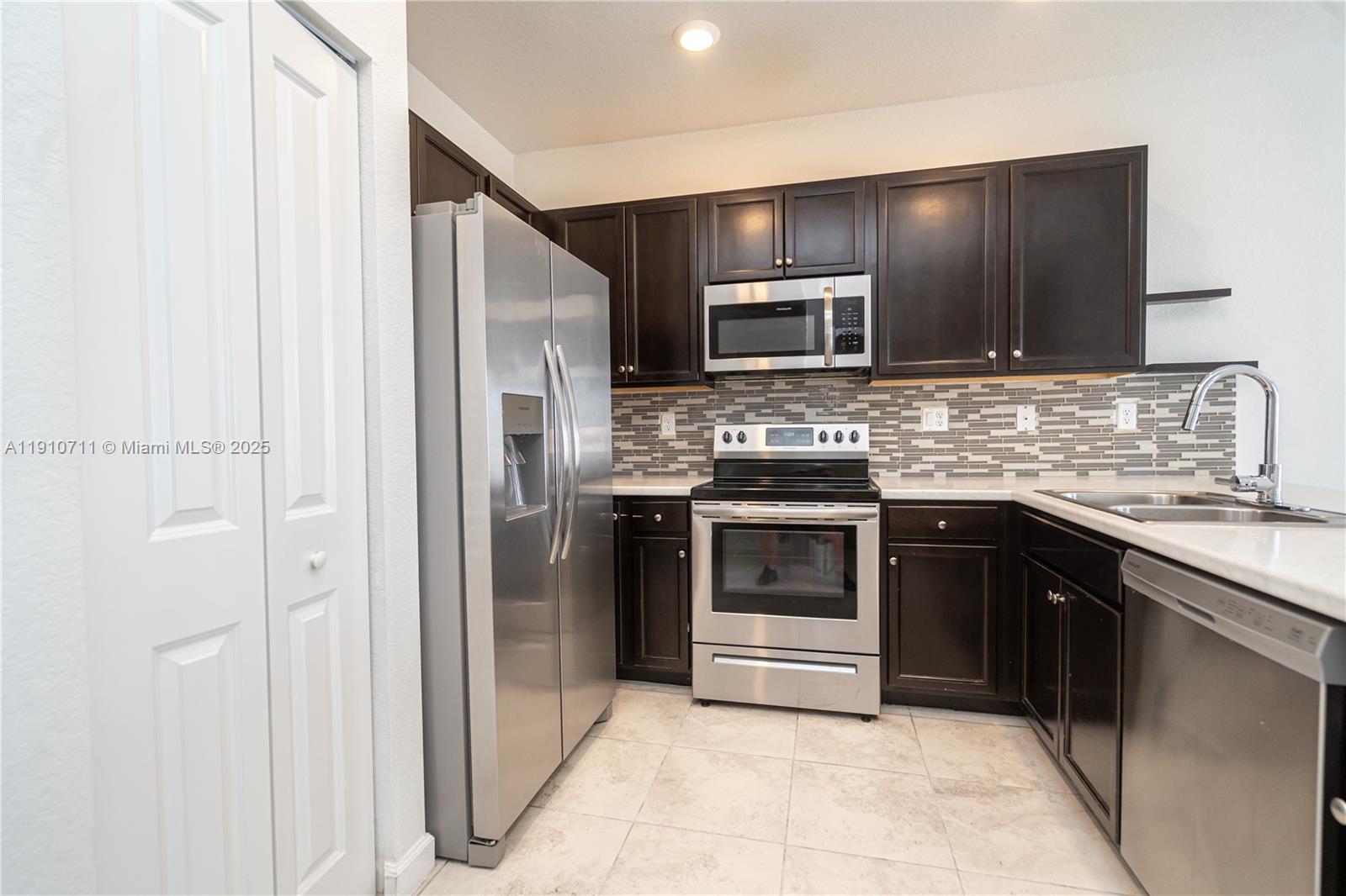 11374 Southwest 254th Terrace Homestead, FL 33032 - Photo 3 of 51 a kitchen with stainless steel appliances granite countertop a refrigerator and a stove top oven