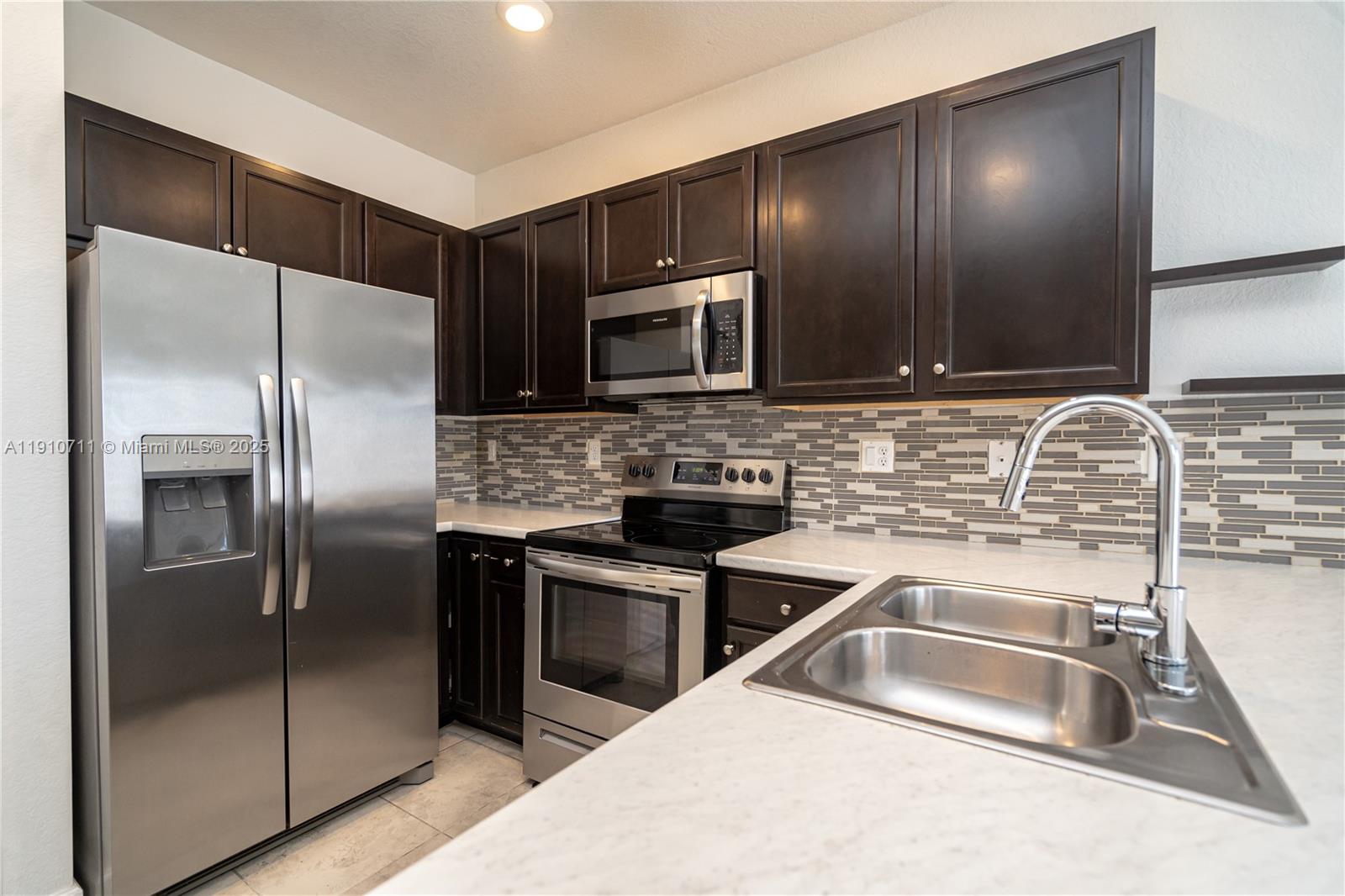 11374 Southwest 254th Terrace Homestead, FL 33032 - Photo 5 of 51 a kitchen with stainless steel appliances granite countertop a sink and a microwave