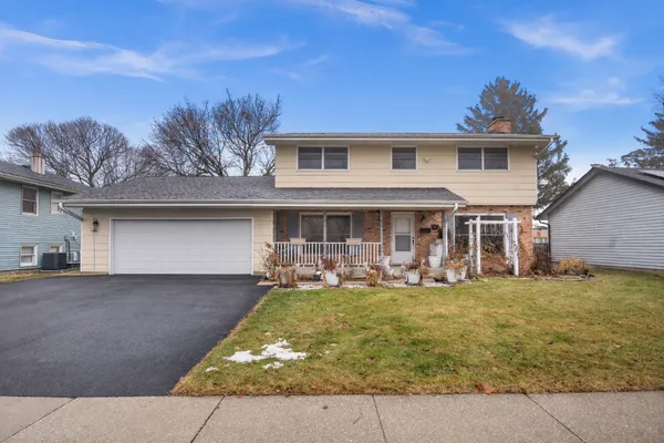 a front view of a house with a garden and trees
