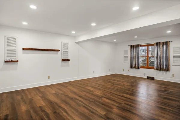 an empty room with wooden floor and window