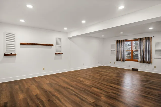 an empty room with wooden floor and window