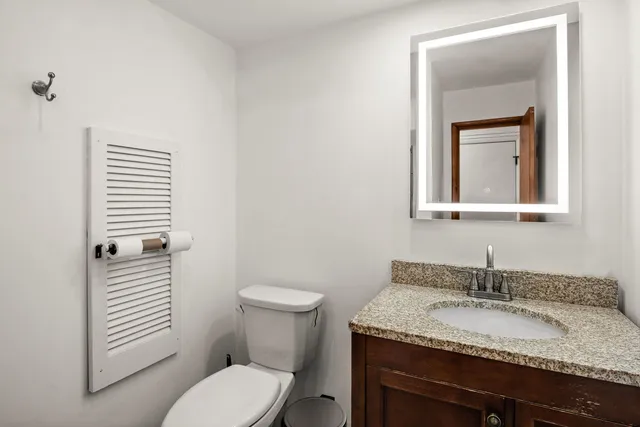 a bathroom with a granite countertop toilet sink and mirror