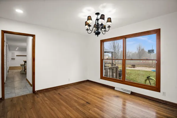 a view of a room with wooden floor chandelier and windows