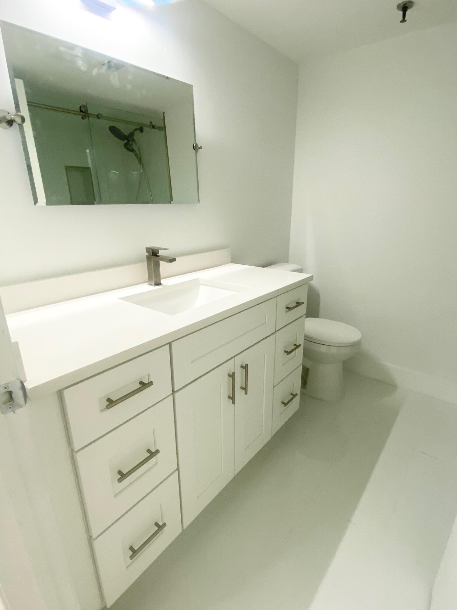 9170 Southwest 14th Street, Unit 4405 Boca Raton, FL 33428 - Photo 24 of 48 a bathroom with a toilet sink and mirror