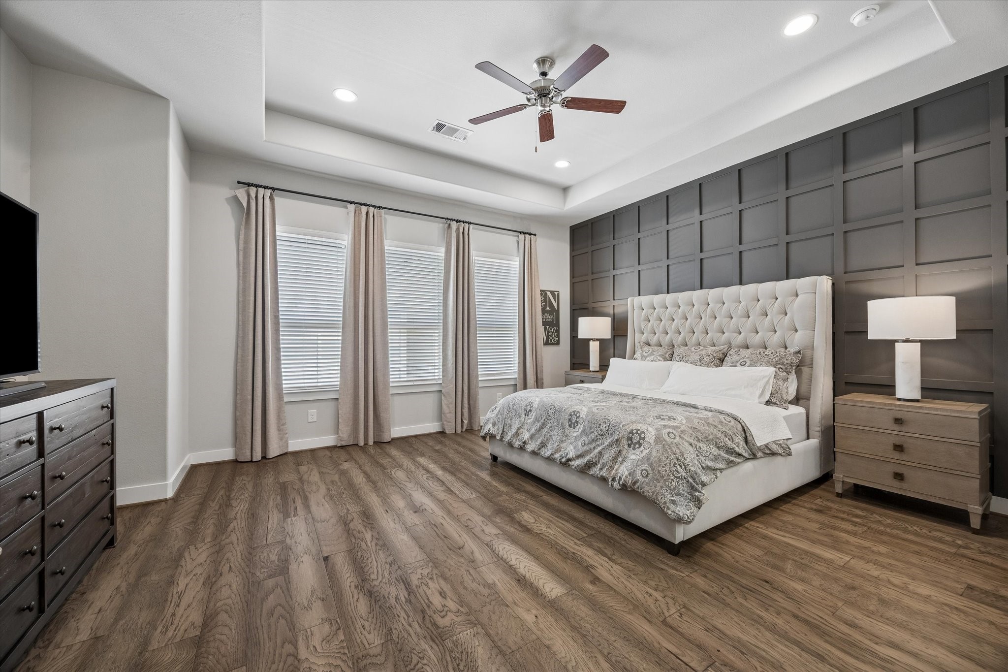1309 West 24th Street, Unit B Houston, TX 77008 - Photo 18 of 22 Huge 18' x 16' primary bedroom with high ceilings, hardwood floor, recessed lighting, ceiling fan and the best part is the custom millwork accent wall installed by the current owners.
