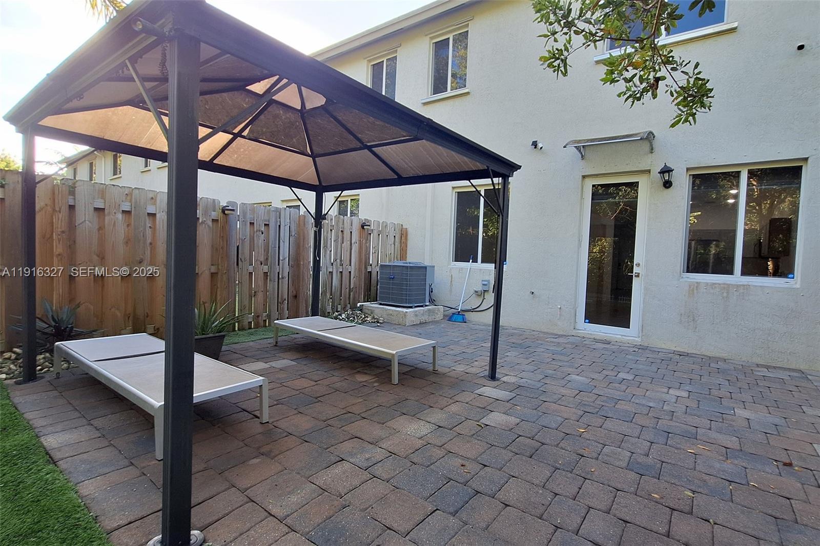 1325 Northwest 208th Street Miami Gardens, FL 33169 - Photo 31 of 38 a view of a patio with a table and chairs under an umbrella