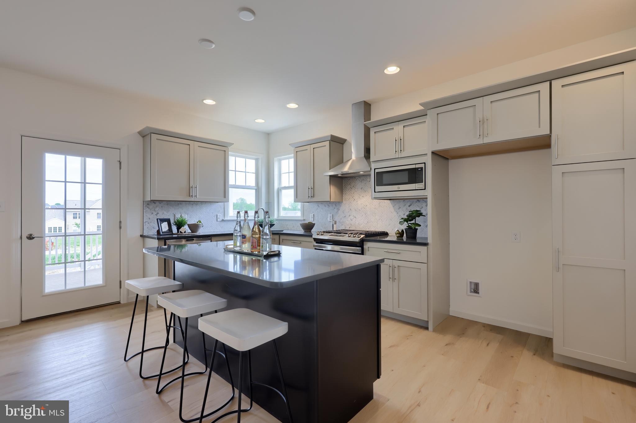 361 Autumn Harvest Lane, Unit 2 Lititz, PA 17543 - Photo 16 of 50 a kitchen with kitchen island a stove a table and chairs in it