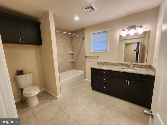 a bathroom with a granite countertop sink a toilet mirror and bathtub
