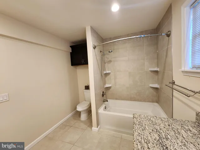 a bathroom with a granite countertop bathtub shower and toilet