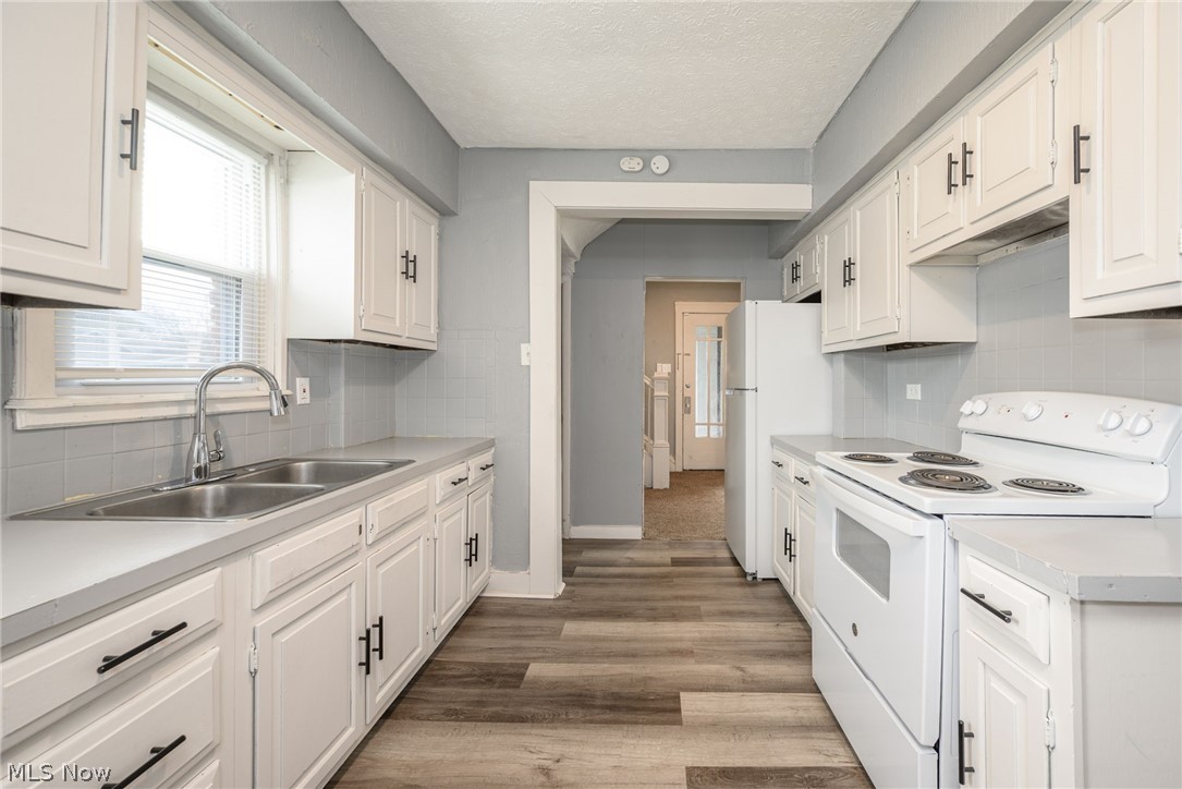 1603 Hampton Road Akron, OH 44305 - Photo 16 of 50 Kitchen with white electric range, light countertops, white cabinets, light wood-style flooring, and decorative backsplash