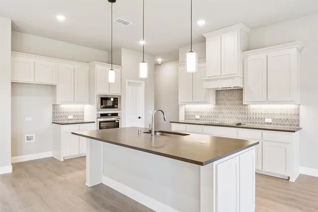 a kitchen with kitchen island granite countertop a sink a counter space appliances and cabinets