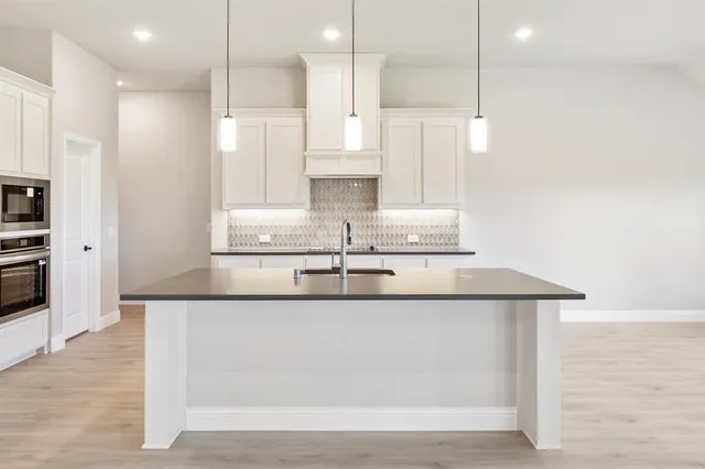 a kitchen with kitchen island stainless steel appliances sink refrigerator and microwave