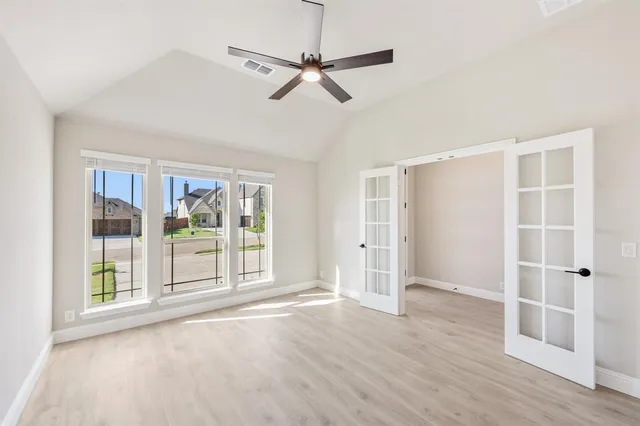 a view of an empty room with a window and wooden floor