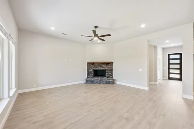 an empty room with chandelier fan and windows