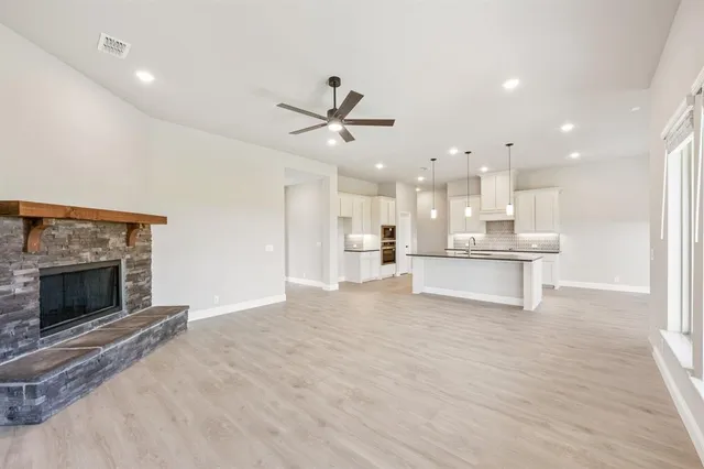 a view of an empty room with kitchen and fireplace