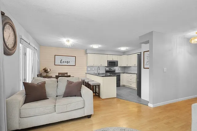 a living room with furniture a kitchen view and a refrigerator