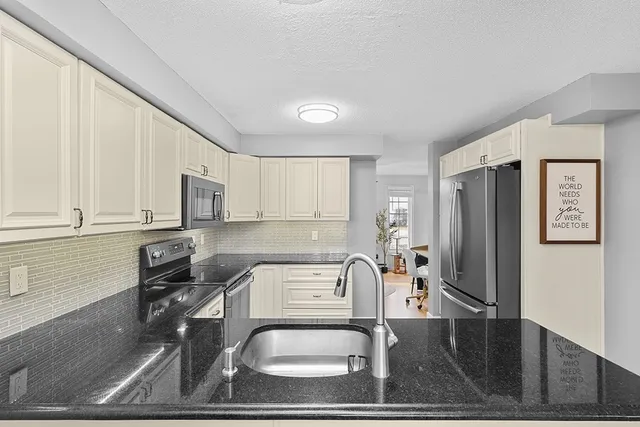 a kitchen with stainless steel appliances granite countertop a refrigerator a stove and white cabinets with wooden floor