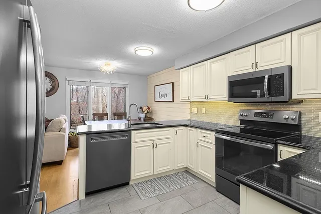 a kitchen with stainless steel appliances granite countertop a stove top oven a sink dishwasher a refrigerator and a microwave