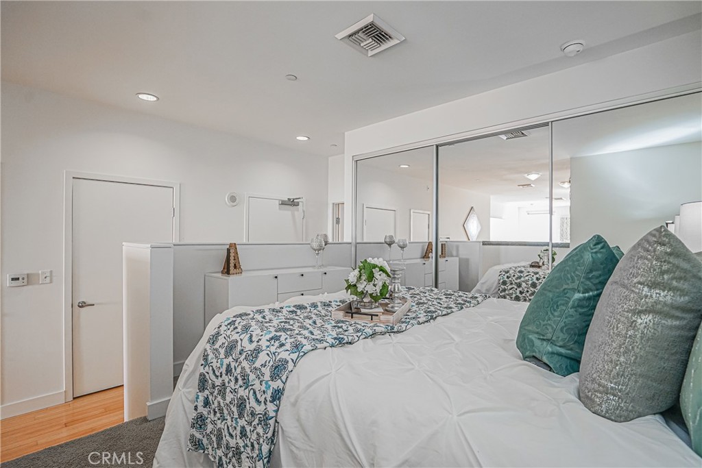 3810 Wilshire Boulevard, Unit 1409 Los Angeles, CA 90010 - Photo 12 of 41 a bedroom with a bed and a mirror