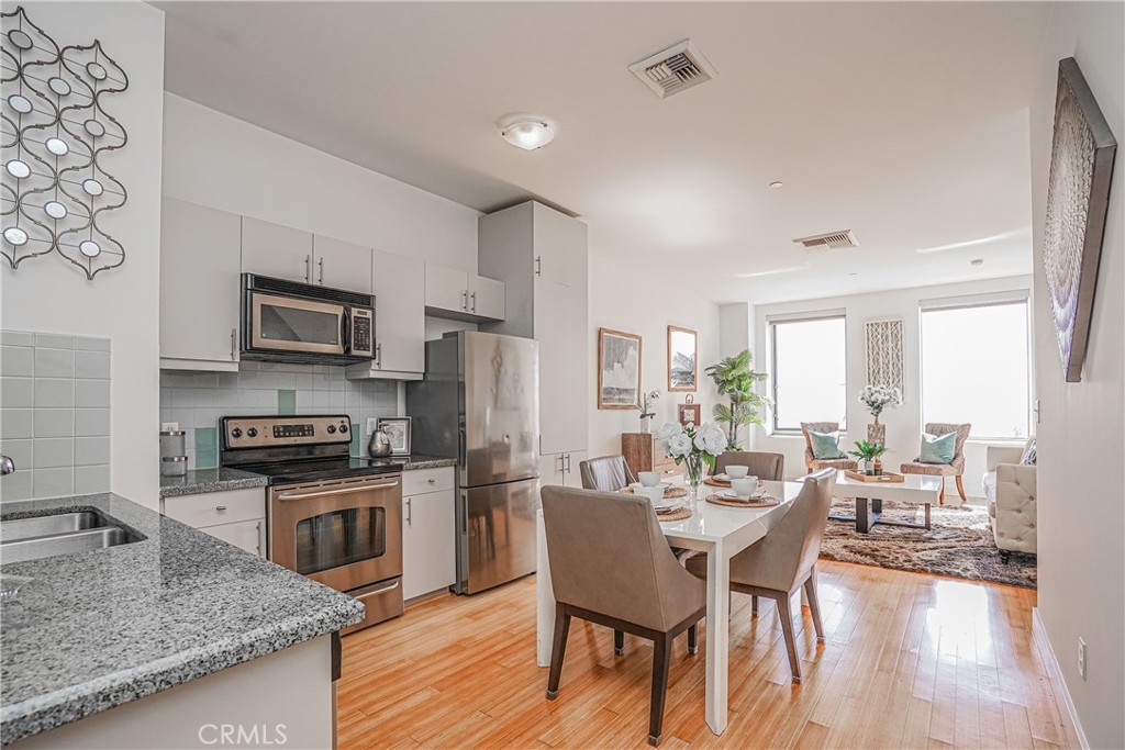3810 Wilshire Boulevard, Unit 1409 Los Angeles, CA 90010 - Photo 23 of 41 a kitchen with stainless steel appliances granite countertop a stove top oven a sink dishwasher a dining table and chairs with wooden floor