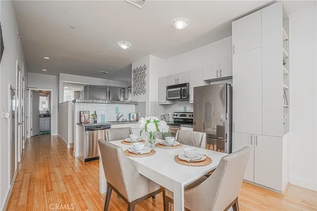 a kitchen with stainless steel appliances kitchen island granite countertop a refrigerator a stove top oven a sink dishwasher and white countertops with wooden floor