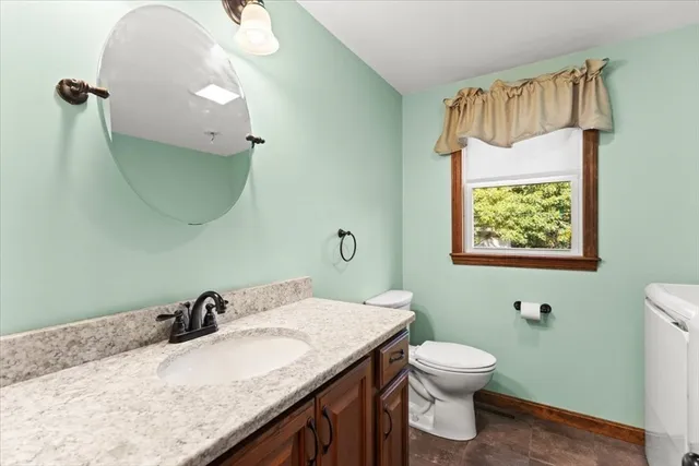 a bathroom with a granite countertop sink a toilet and a mirror