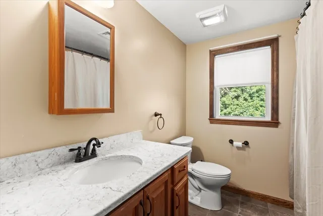 a bathroom with a granite countertop sink toilet and a mirror