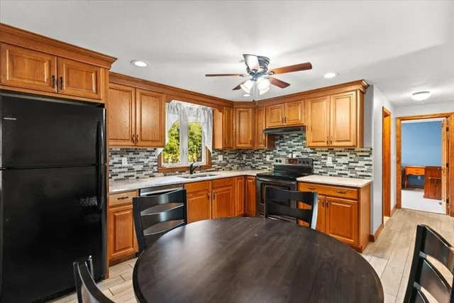 a kitchen with stainless steel appliances granite countertop a stove top oven a sink a dining table and chairs
