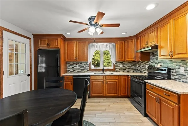 a kitchen with stainless steel appliances granite countertop wooden cabinets a sink dishwasher a stove and a refrigerator with wooden floor