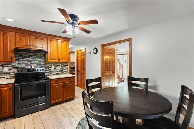 a kitchen with granite countertop a stove a sink a dining table and chairs