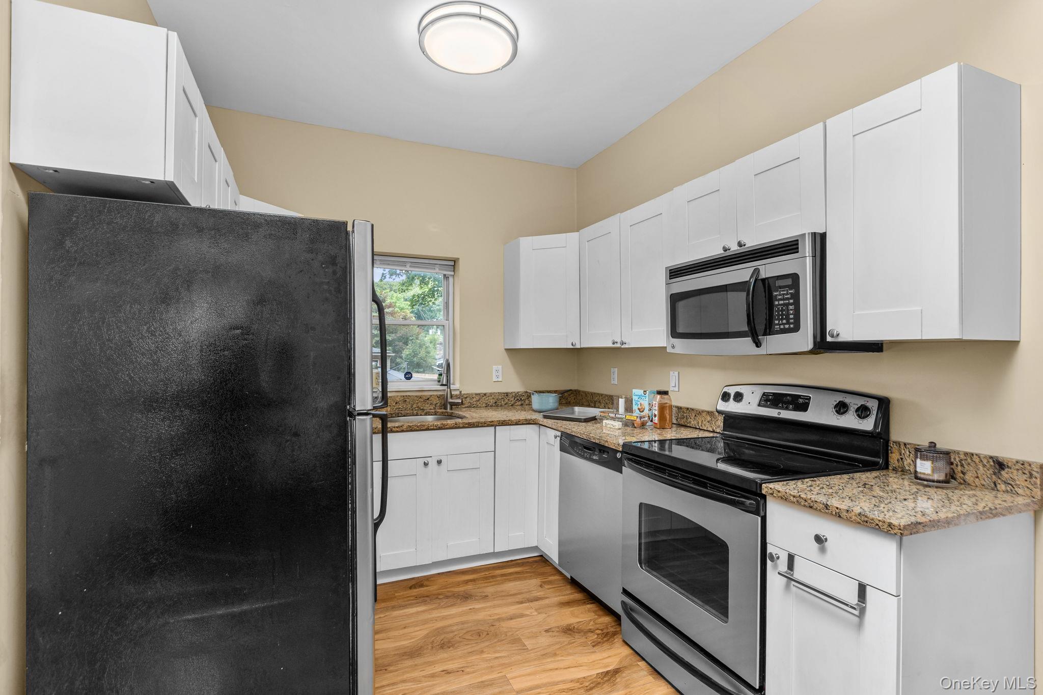 10 Batavia Road Patterson, NY 12563 - Photo 14 of 42 Well-appointed kitchen featuring white cabinetry, granite-finish countertops, stainless steel appliances, a built-in microwave, and wood-finish flooring.