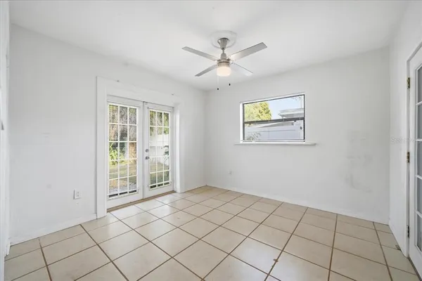a view of an empty room with window and chandelier fan
