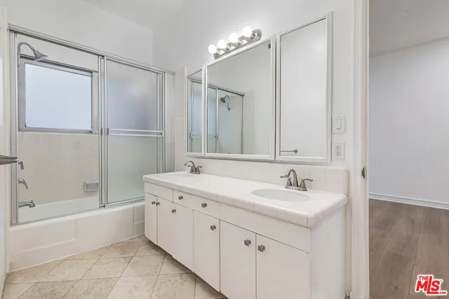 a bathroom with a double vanity sink mirror and bathtub
